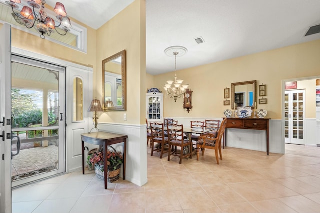 dining room with a chandelier, wainscoting, visible vents, and light tile patterned floors