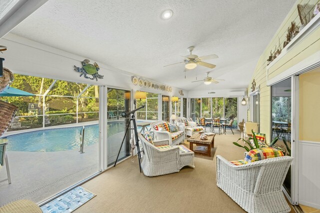 sunroom with a ceiling fan, a wealth of natural light, an AC wall unit, and lofted ceiling