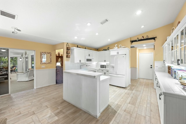 kitchen with wood finish floors, visible vents, a barn door, glass insert cabinets, and white appliances