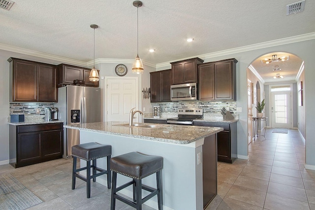 kitchen featuring arched walkways, a breakfast bar area, visible vents, appliances with stainless steel finishes, and a sink