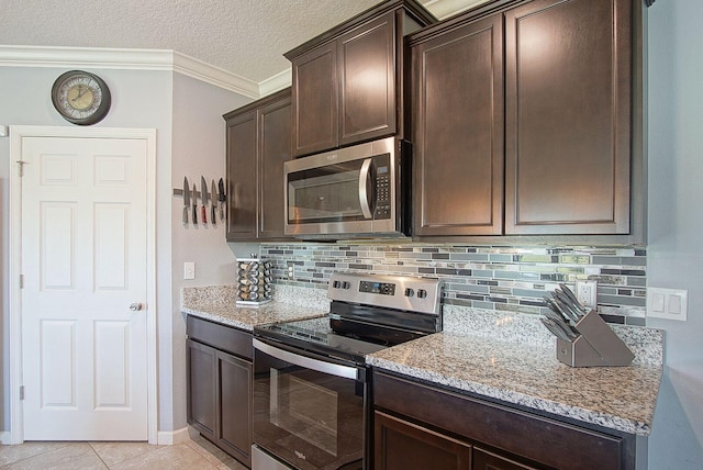 kitchen featuring light stone counters, stainless steel appliances, dark brown cabinets, ornamental molding, and decorative backsplash