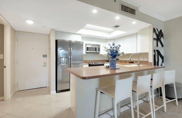 kitchen with a peninsula, visible vents, appliances with stainless steel finishes, and a sink