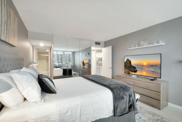 bedroom with a closet, visible vents, baseboards, and ensuite bath