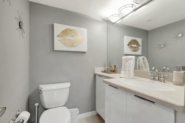 bathroom with toilet, tile patterned floors, baseboards, and vanity