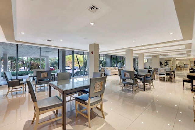 dining room with visible vents, a tray ceiling, light tile patterned flooring, floor to ceiling windows, and recessed lighting