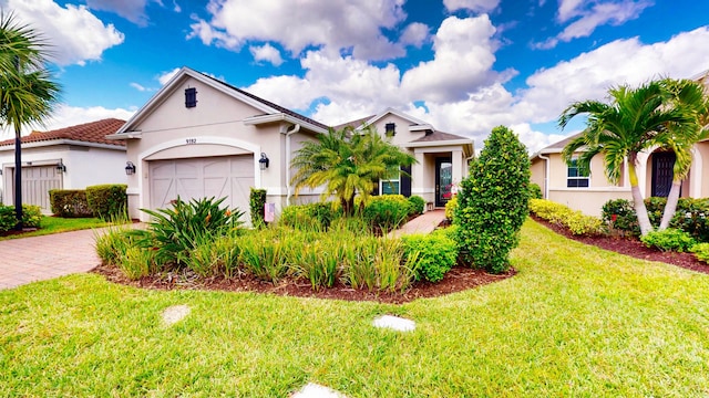 view of front facade featuring a garage, a front lawn, decorative driveway, and stucco siding