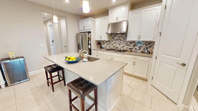9592 SW Royal Poinciana Dr, Port Saint Lucie, FL 34987 - kitchen featuring decorative backsplash, appliances with stainless steel finishes, under cabinet range hood, a sink, and light tile patterned flooring