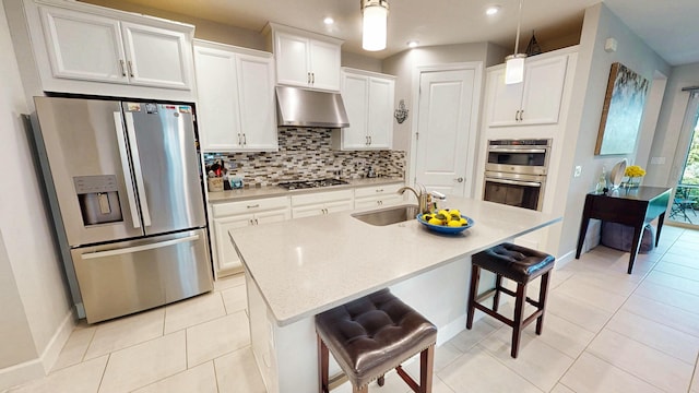 9592 SW Royal Poinciana Dr, Port Saint Lucie, FL 34987 - kitchen with light tile patterned floors, under cabinet range hood, a sink, appliances with stainless steel finishes, and decorative backsplash