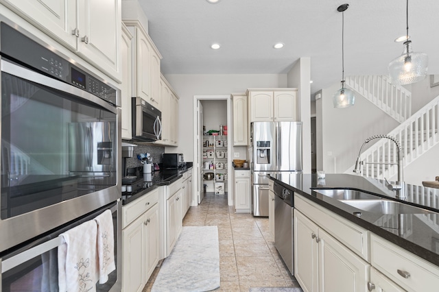 kitchen featuring recessed lighting, hanging light fixtures, decorative backsplash, appliances with stainless steel finishes, and a sink