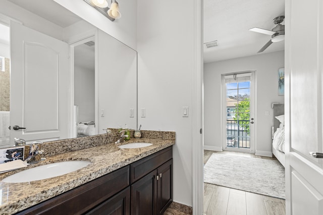 ensuite bathroom with double vanity, wood finished floors, a sink, and visible vents