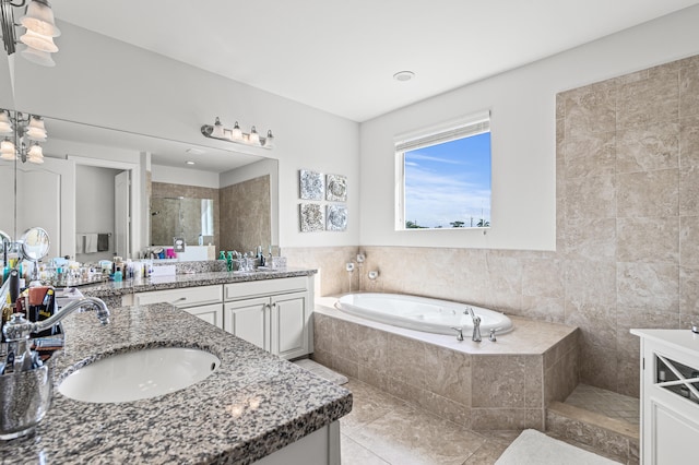 full bath featuring a garden tub, a stall shower, two vanities, and a sink