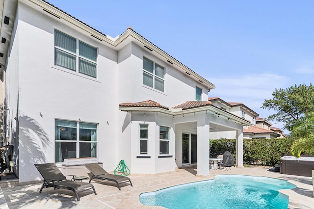 rear view of property with a fenced in pool, a tile roof, stucco siding, a patio area, and fence