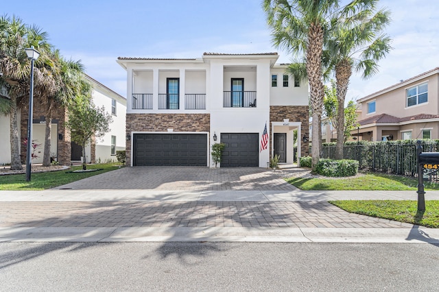 view of front of house with an attached garage, fence, decorative driveway, and stucco siding