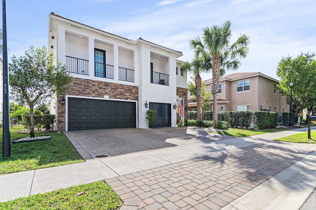 townhome / multi-family property with decorative driveway, an attached garage, fence, and stucco siding