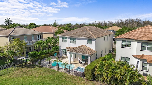 rear view of property with a fenced in pool, a lawn, a fenced backyard, a tile roof, and a patio area