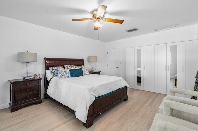 bedroom with ceiling fan, light wood-style flooring, visible vents, baseboards, and two closets