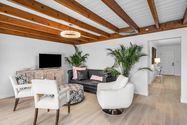 living area featuring visible vents, light wood finished floors, beam ceiling, and baseboards