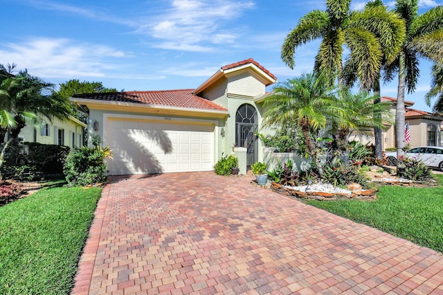 mediterranean / spanish-style home featuring a garage, stucco siding, a tile roof, decorative driveway, and a front yard