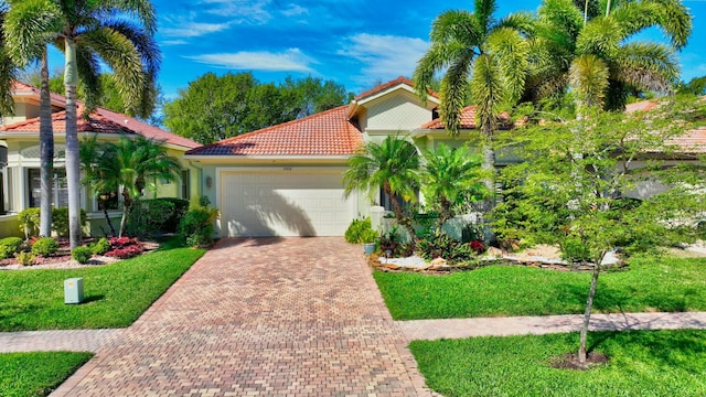 mediterranean / spanish home featuring decorative driveway, stucco siding, a garage, a tiled roof, and a front lawn