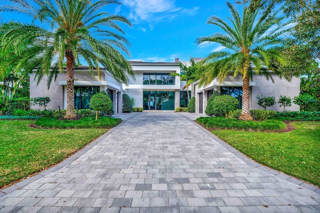 view of front facade featuring a carport, decorative driveway, a front yard, and stucco siding