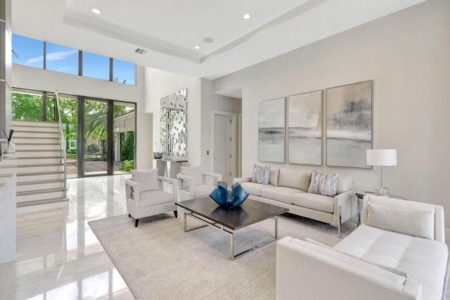 living area featuring stairway, visible vents, a tray ceiling, and recessed lighting