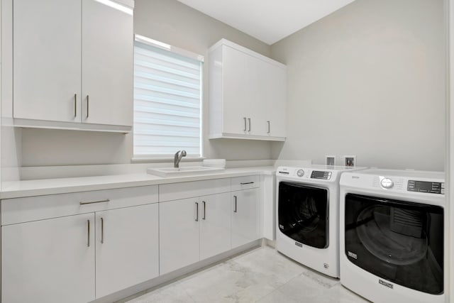 laundry room with washing machine and clothes dryer, a sink, and cabinet space