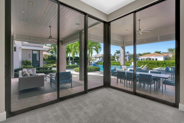 doorway to outside featuring carpet floors and ceiling fan