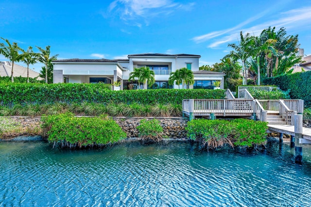 rear view of property with a deck with water view and stucco siding