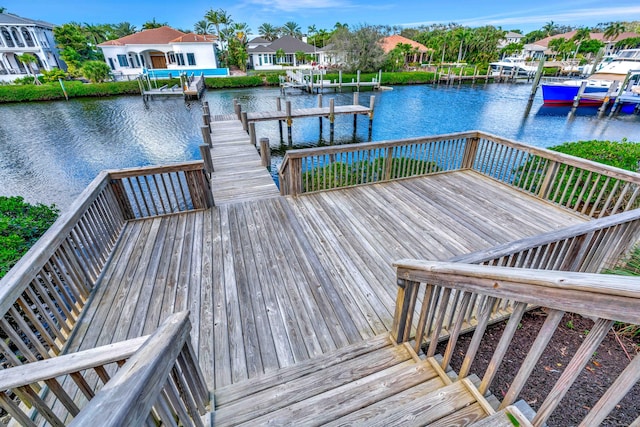 view of dock with a water view, boat lift, and a residential view