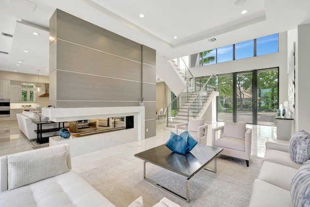 living room featuring visible vents, a towering ceiling, stairway, a tray ceiling, and recessed lighting