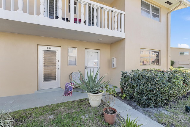 view of exterior entry featuring a balcony and stucco siding