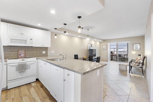 kitchen featuring white appliances, tasteful backsplash, open floor plan, a peninsula, and a sink