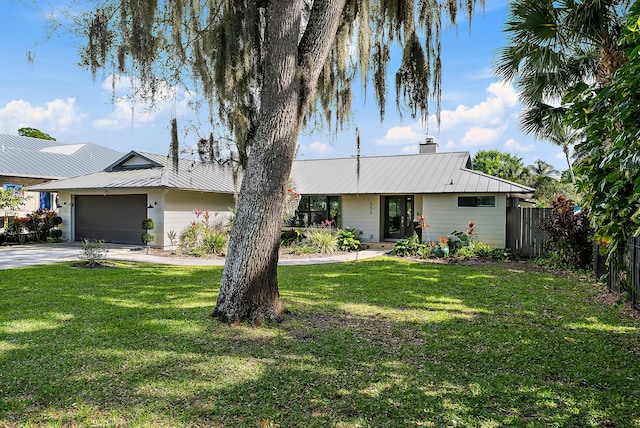 view of front of house featuring a garage, fence, metal roof, and a front yard