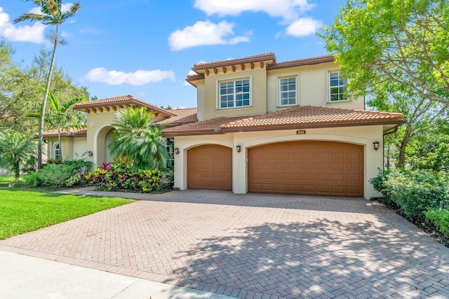 mediterranean / spanish house featuring decorative driveway, a tile roof, and stucco siding