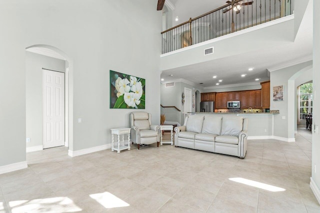 living room featuring arched walkways, ornamental molding, visible vents, and baseboards