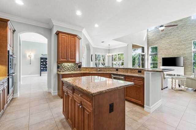 kitchen with light tile patterned floors, appliances with stainless steel finishes, open floor plan, light stone counters, and a peninsula