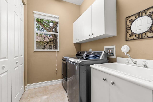 laundry room with cabinet space, light tile patterned floors, baseboards, washer and dryer, and a sink