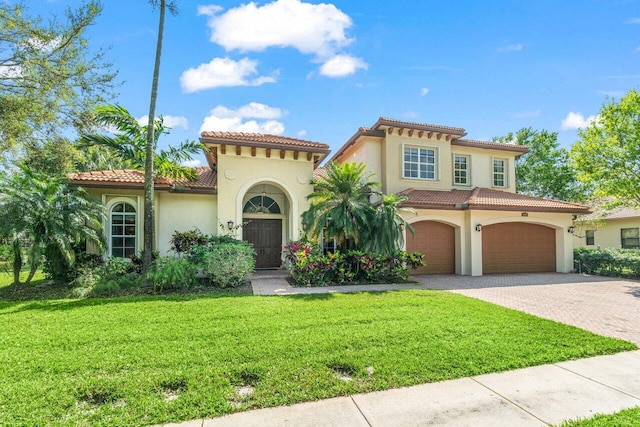 mediterranean / spanish-style home featuring decorative driveway, a tile roof, a front lawn, and stucco siding