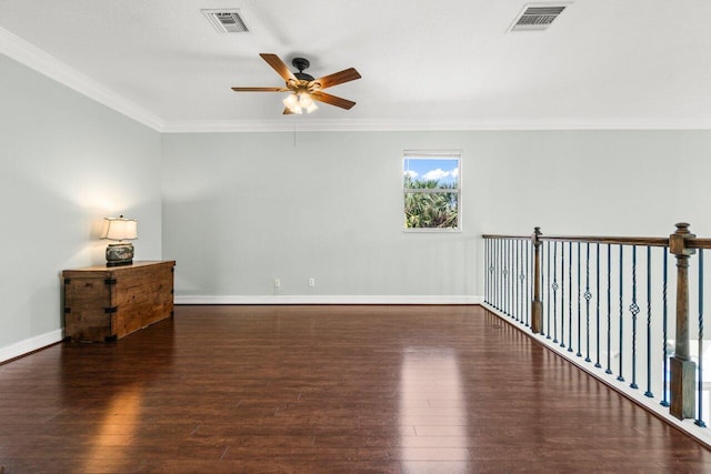 spare room with wood-type flooring, visible vents, baseboards, and ornamental molding