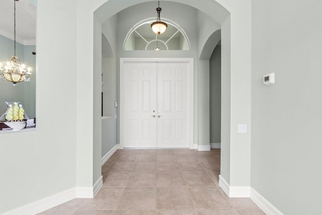 tiled foyer with baseboards and a chandelier