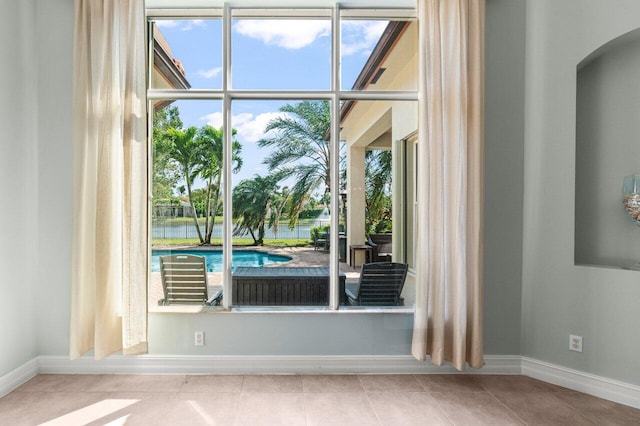 entryway featuring baseboards, tile patterned flooring, and a healthy amount of sunlight