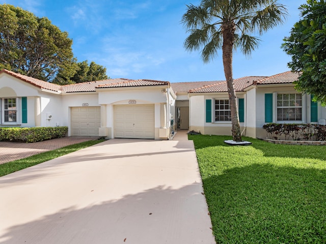 mediterranean / spanish home featuring a garage, a front yard, concrete driveway, and stucco siding