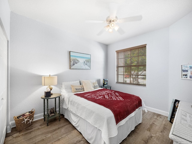 bedroom with ceiling fan, wood finished floors, and baseboards