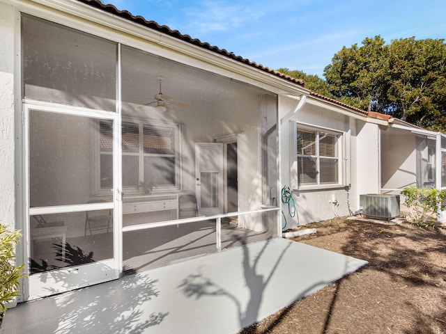 exterior space with a tile roof, central AC, and stucco siding