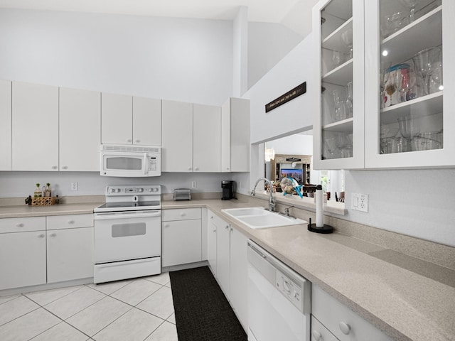 kitchen featuring light countertops, glass insert cabinets, light tile patterned flooring, a sink, and white appliances