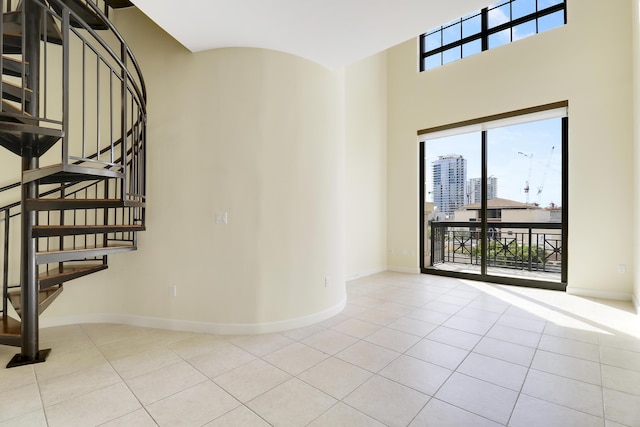 spare room with a healthy amount of sunlight, baseboards, and light tile patterned flooring