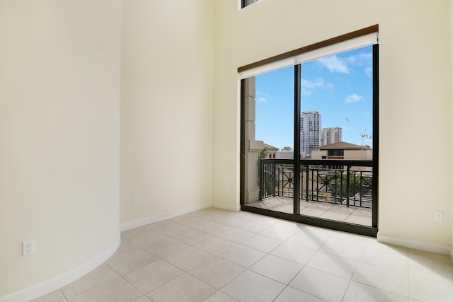 spare room featuring a city view, baseboards, and light tile patterned floors