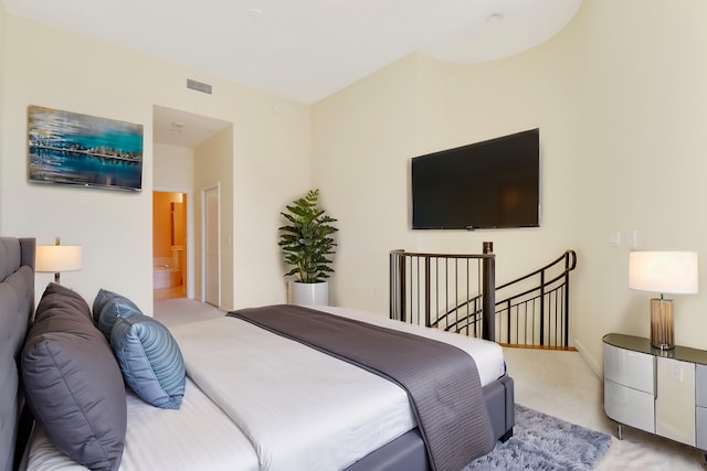 carpeted bedroom with ensuite bath and visible vents