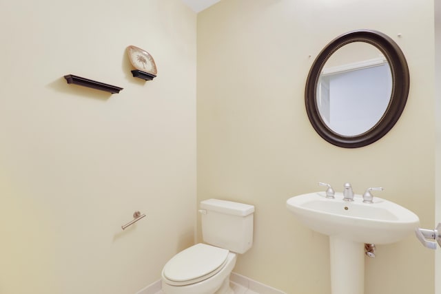 bathroom featuring a sink, toilet, and baseboards