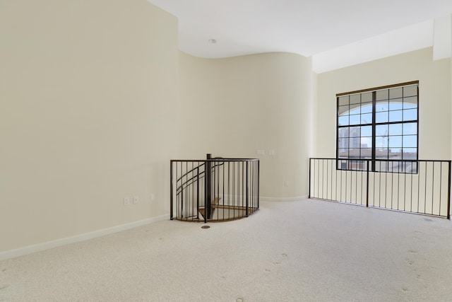 empty room featuring carpet floors, lofted ceiling, and baseboards